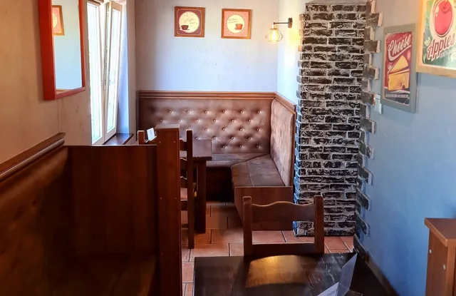 Przytulny kącik w restauracji z tapicerowaną ławą i ceglanym filarem