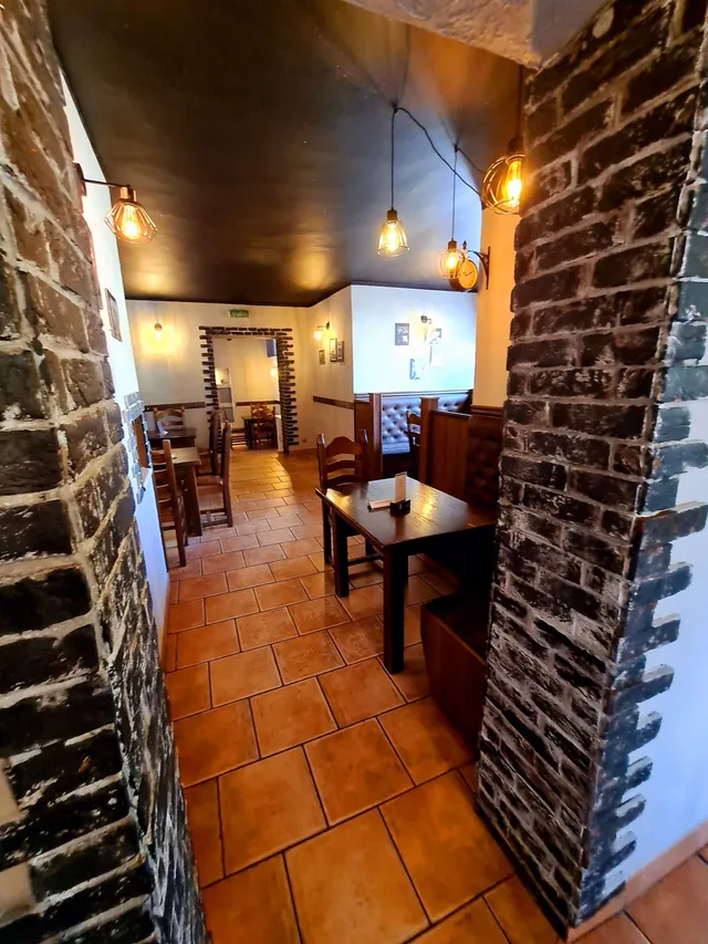 Wnętrze restauracji Mariano z kamiennymi ścianami i drewnianymi stolikami