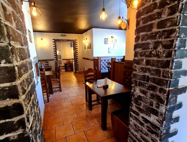 Letni ogródek restauracji ze stolikami pod parasolami i kwitnącymi krzewami